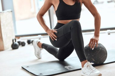 Genç bayan sporcu spor salonunda kaslarını esnetiyor.