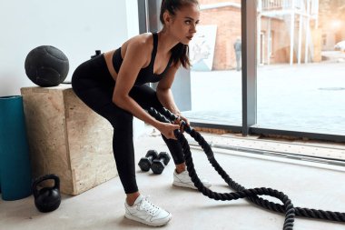 Spor kıyafetli dinlenen kadın elinde çapraz ip tutuyor.