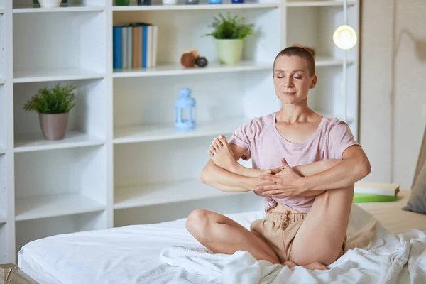 Söt ung kaukasiska flicka på morgonen praktiserar yoga på vit säng — Stockfoto
