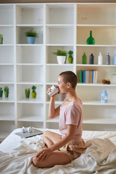 Charmig kaukasisk kvinna med en kopp te på sängen — Stockfoto