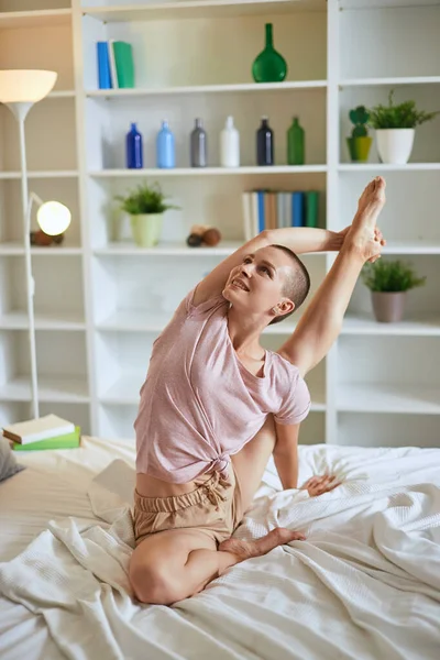 Jeune femme de fitness en pyjama faisant des exercices à la maison sur le lit. Mode de vie sain — Photo