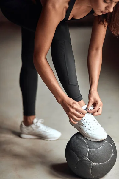 Junges Mädchen schnürt Laufschuh in Turnhalle — Stockfoto