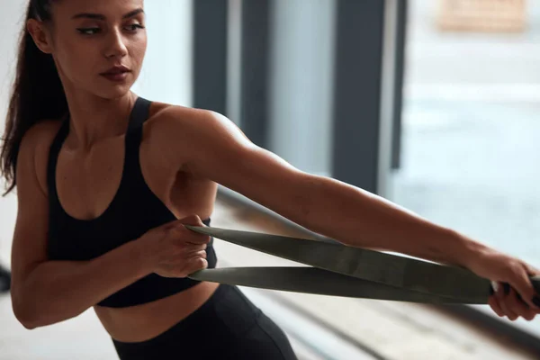 Spor salonundaki beyaz atletik kadın vücut geliştirici elastik ip egzersizleri yapıyor. — Stok fotoğraf