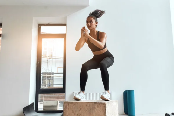 Jovem muscular feminino fazendo salto agachamentos no ajuste caixa — Fotografia de Stock