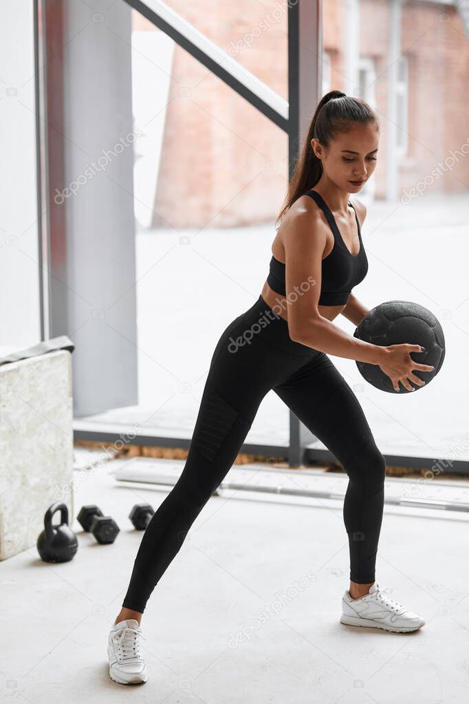 Fitness girl working out at white gym using ball