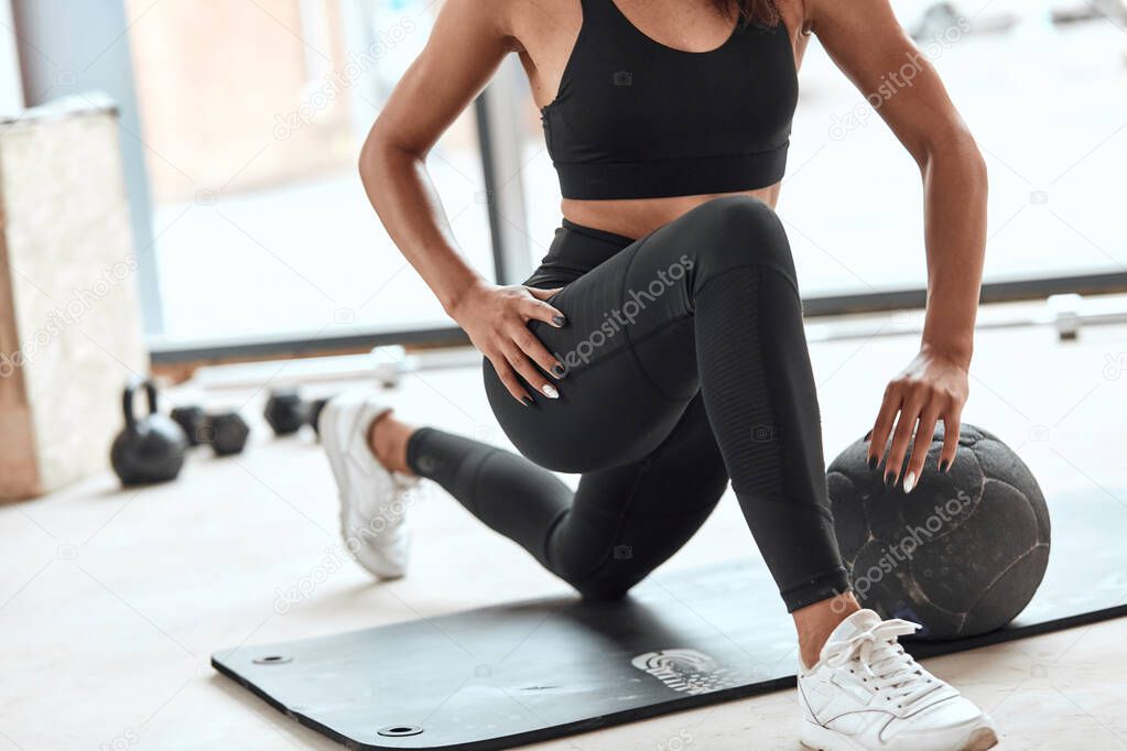 young femaleathlete stretching muscle legs in gym