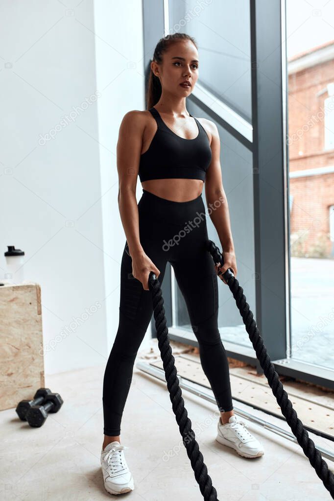 Beautiful woman use training ropes in gym