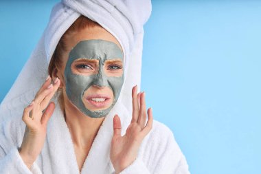 Yüz bakımı. Sinirli beyaz kadın, yüzü için maske kullanıyor.