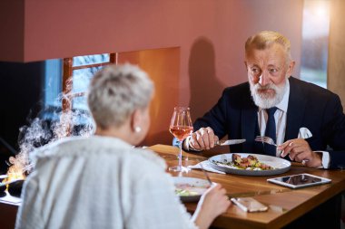 Üst düzey Kafkasyalı çift lokantada yemek yerken sohbet ediyorlar.