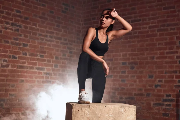 Descansando. Mujer de fitness de aspecto cansado de pie cerca de la caja en el gimnasio — Foto de Stock