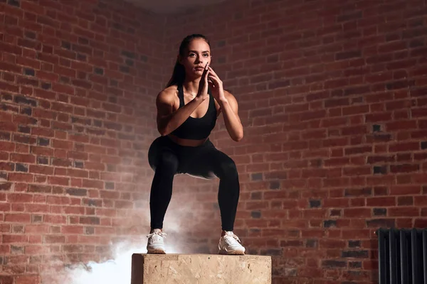 Schöne Bodybuilderin springt auf Holzkiste — Stockfoto