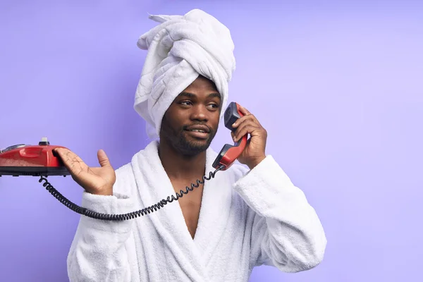 Hombre africano sosteniendo un teléfono fijo y hablando aislado sobre fondo blanco . — Foto de Stock