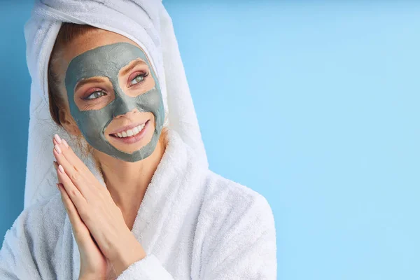 Mooie vrouw met handdoek op het hoofd brengt masker op gezicht — Stockfoto