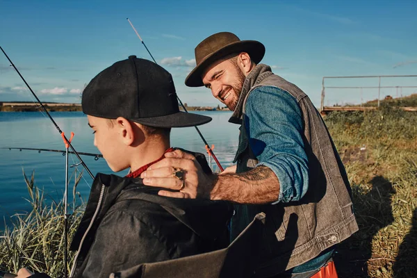 Father and son fishing together on sunny day