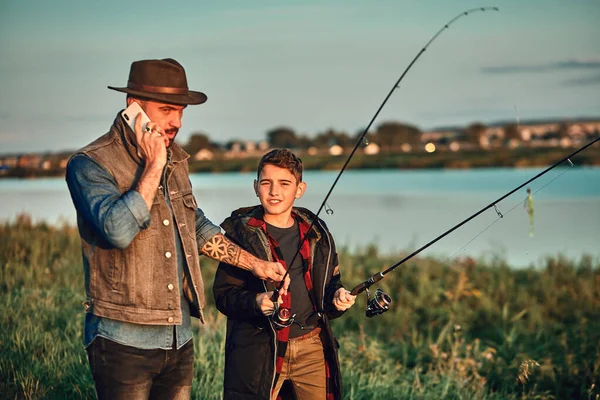 A primeira pesca conjunta de pai adulto e filho adolescente em dia quente e ensolarado . — Fotografia de Stock