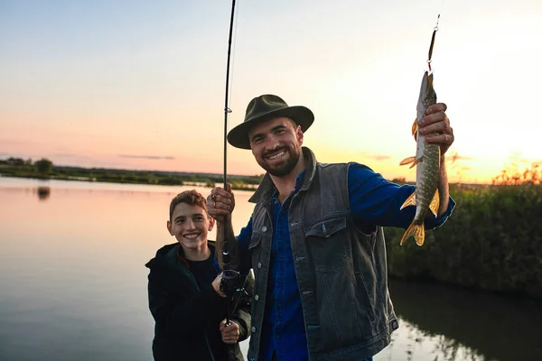 La prima pesca congiunta di padre adulto e figlio adolescente in giornata calda e soleggiata . — Foto Stock