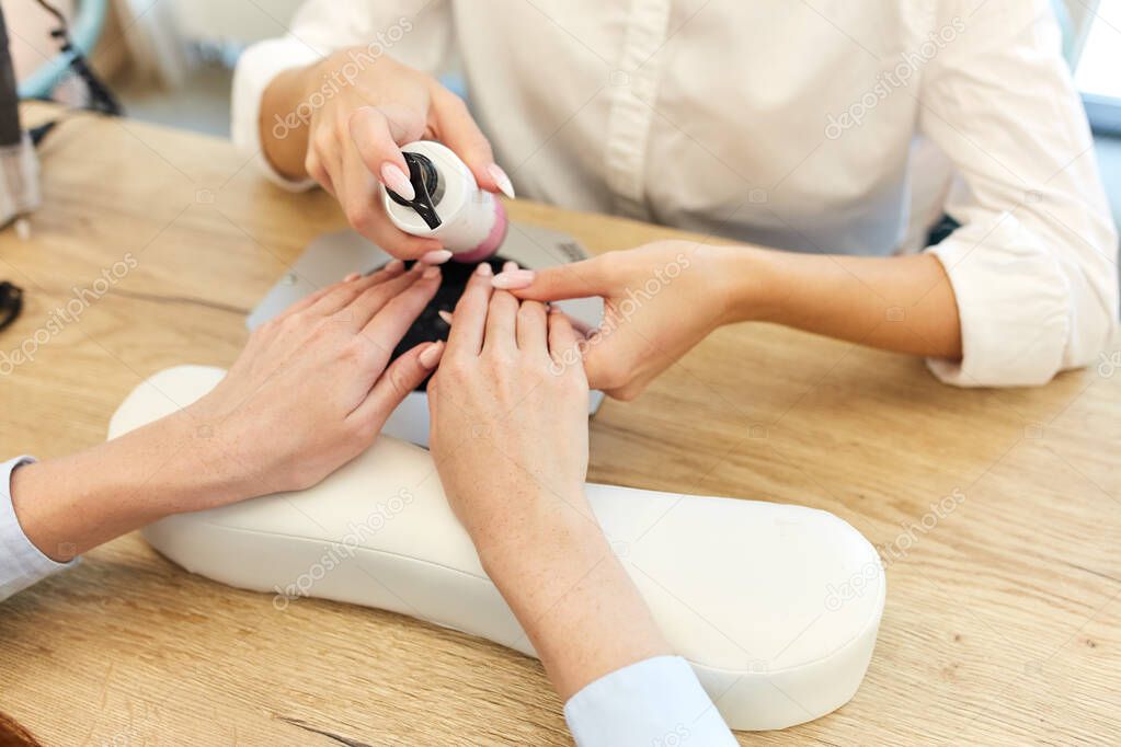 Finger nail care by manicurist in beauty salon
