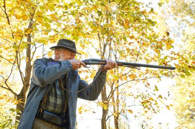 Silahlı kıdemli avcı tüfeğini ateşlemeye hazır.