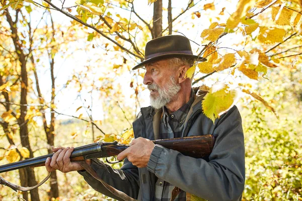 Senior Jäger mit seinem Gewehr im Herbstwald — Stockfoto