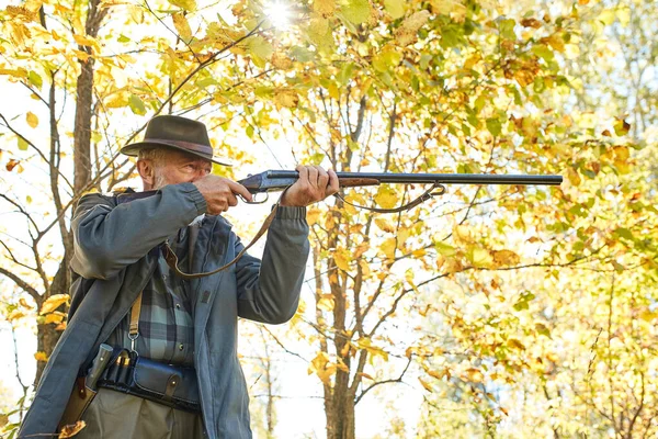 Sénior cazador con su rifle en el bosque de otoño — Foto de Stock