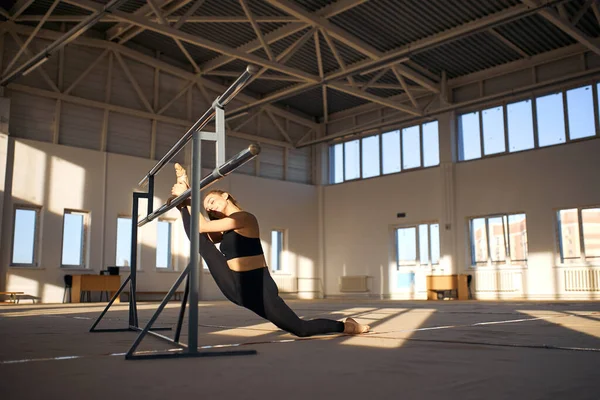 Молодая гимнастка занимается акробатическими упражнениями в спортзале — стоковое фото