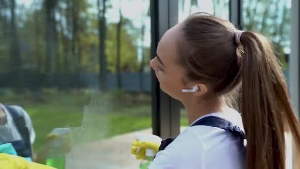 Vista posteriore sulla giovane donna più pulita lavaggio vetro della finestra — Video Stock