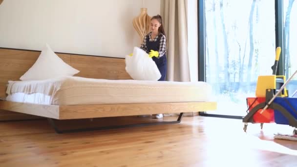 Young woman janitor making bed in living room — Stock Video