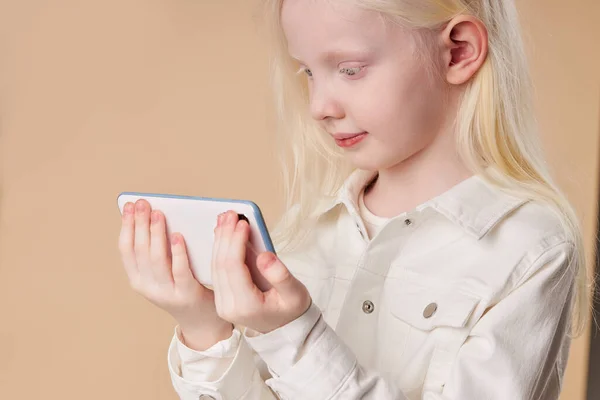 Beyaz akıllı telefonu tek başına elinde tutan albino çocuk. — Stok fotoğraf