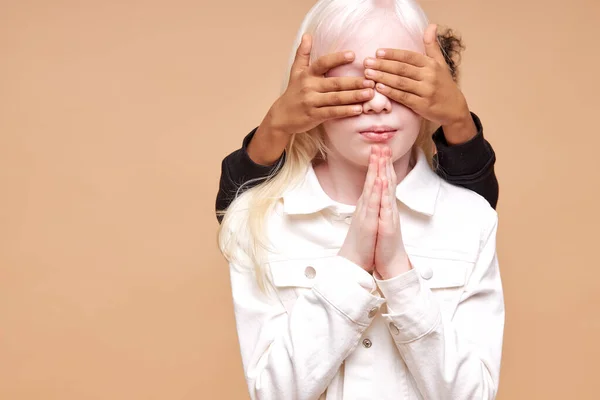 Irreconhecível menino africano fechar albino meninas olhos — Fotografia de Stock