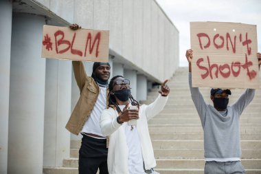 Siyahların hayatı önemli protestolar küresel hale geliyor. Sokakta posterleri olan üç Afroamerikalı.
