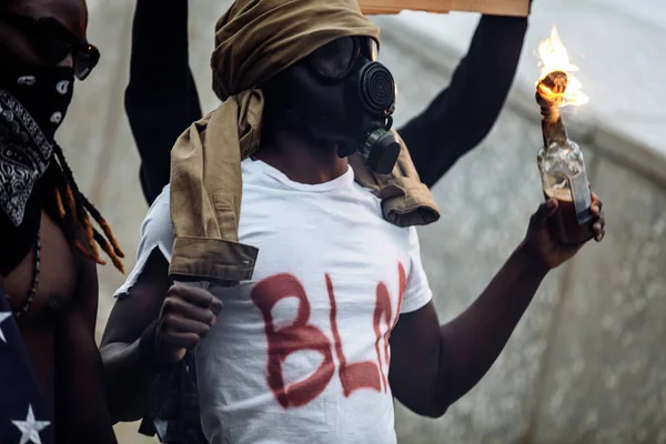 愤怒的黑人戴着防毒面具暴动，放火焚烧瓶子 — 图库照片