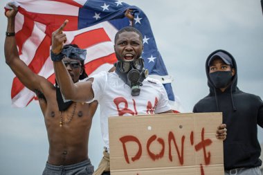 Siyahların hayatı önemli protestolar küresel hale geliyor. Sokakta posterleri olan üç Afroamerikalı.