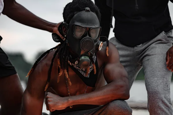 portrait of black shirtless man in gas mask