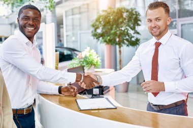 Kafkasyalı danışman Afrika kökenli Amerikalı kesiciyle tokalaşıyor.