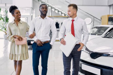 Araba galerisinde araba satan kendine güvenen beyaz bir satıcı.