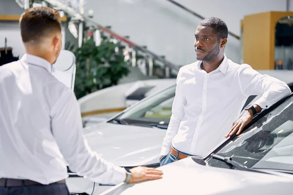 Kendine güvenen bir satıcı, arabanın özelliklerinden müşteriye bahseder. — Stok fotoğraf