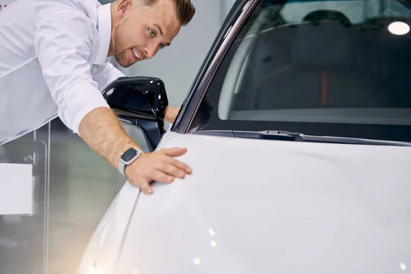 Привабливий клієнт стоїть поруч з білим розкішним автомобілем в дилерстві — стокове фото