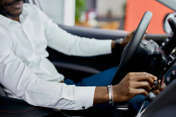 Обрезанный черный мужчина осматривает новый автомобиль изнутри — стоковое фото