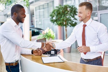 Araba satıcısı ve müşteri el sıkışıyor.