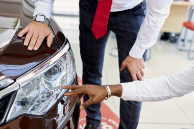 Satış temsilcisi arabanın farları hakkında konuşur, artılarını ve eksilerini müşteriye verir.