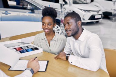 Beyaz tenli satıcı belgeleri müşterilere gösterir.