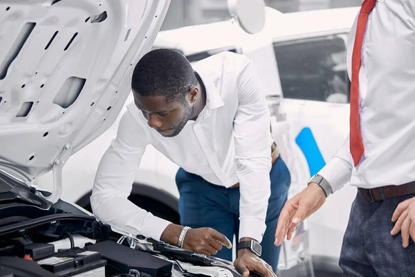 Hombre de negocios africano guapo está examinando un coche antes de comprarlo — Foto de Stock