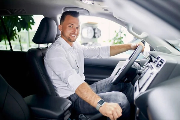 Schöner kaukasischer Kerl sitzt am Steuer eines neuen Automobils — Stockfoto