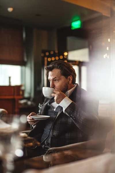 沉思的中年商人一边喝咖啡，一边望着餐馆 — 图库照片