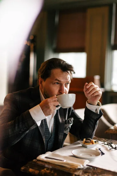 Düşünceli orta yaşlı iş adamı kahve içiyor ve lokantaya bakıyor. — Stok fotoğraf