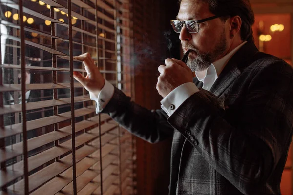 Riflettente uomo barbuto maturo ben vestito in occhiali da fumo tabacco pipa — Foto Stock