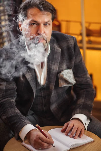 Olgun iş adamı tütün piposu içiyor ve notlar alıyor.. — Stok fotoğraf