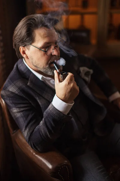 Riflettente uomo barbuto maturo ben vestito in occhiali da fumo tabacco pipa — Foto Stock