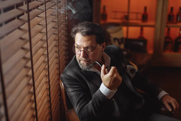 Riflettente uomo barbuto maturo ben vestito in occhiali da fumo tabacco pipa — Foto Stock