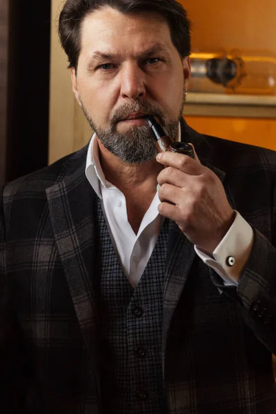 Reflecterende goed geklede volwassen bebaarde man in glazen roken tabakspijp — Stockfoto